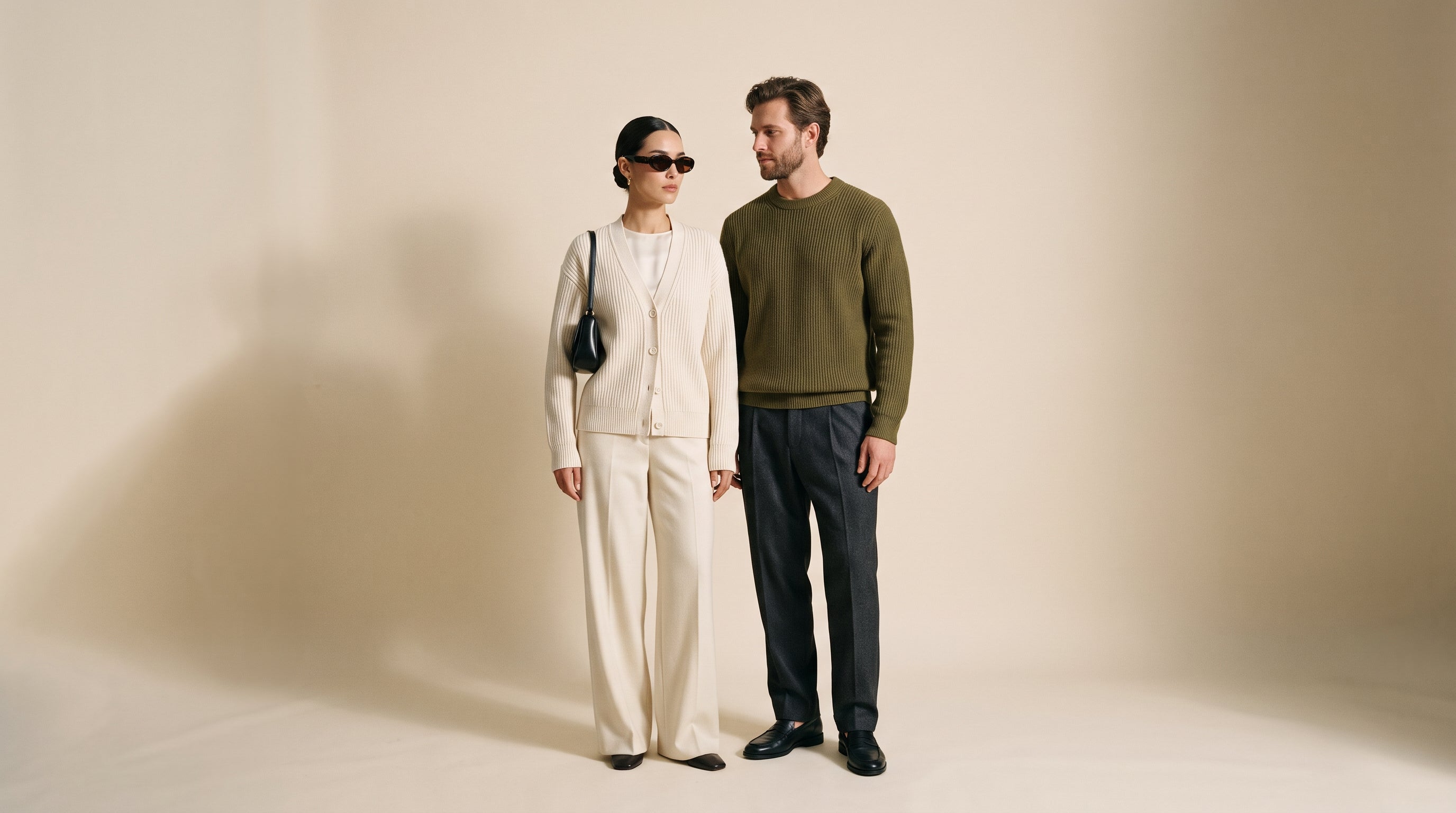 Two models in quiet-luxury knitwear against a warm studio backdrop